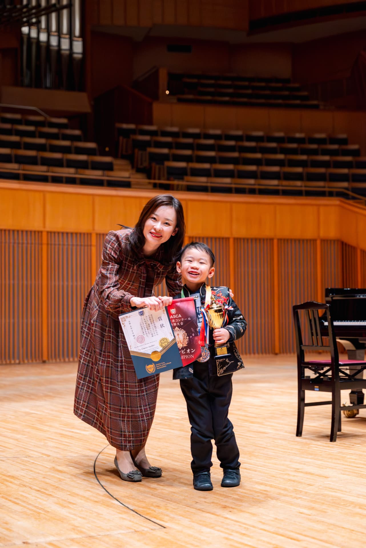 Young champion holding trophy, medal and certificate with presenter