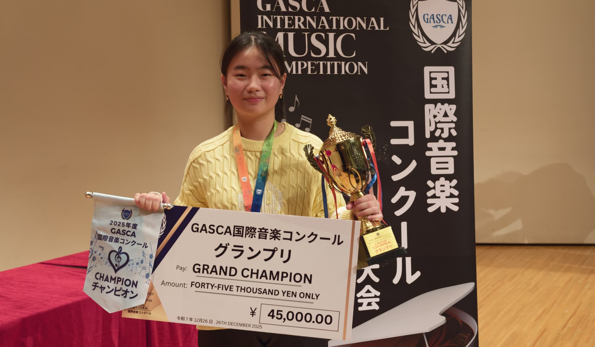 Young Grand Champion holding a trophy, champion pennant and giant cash-prize cheque