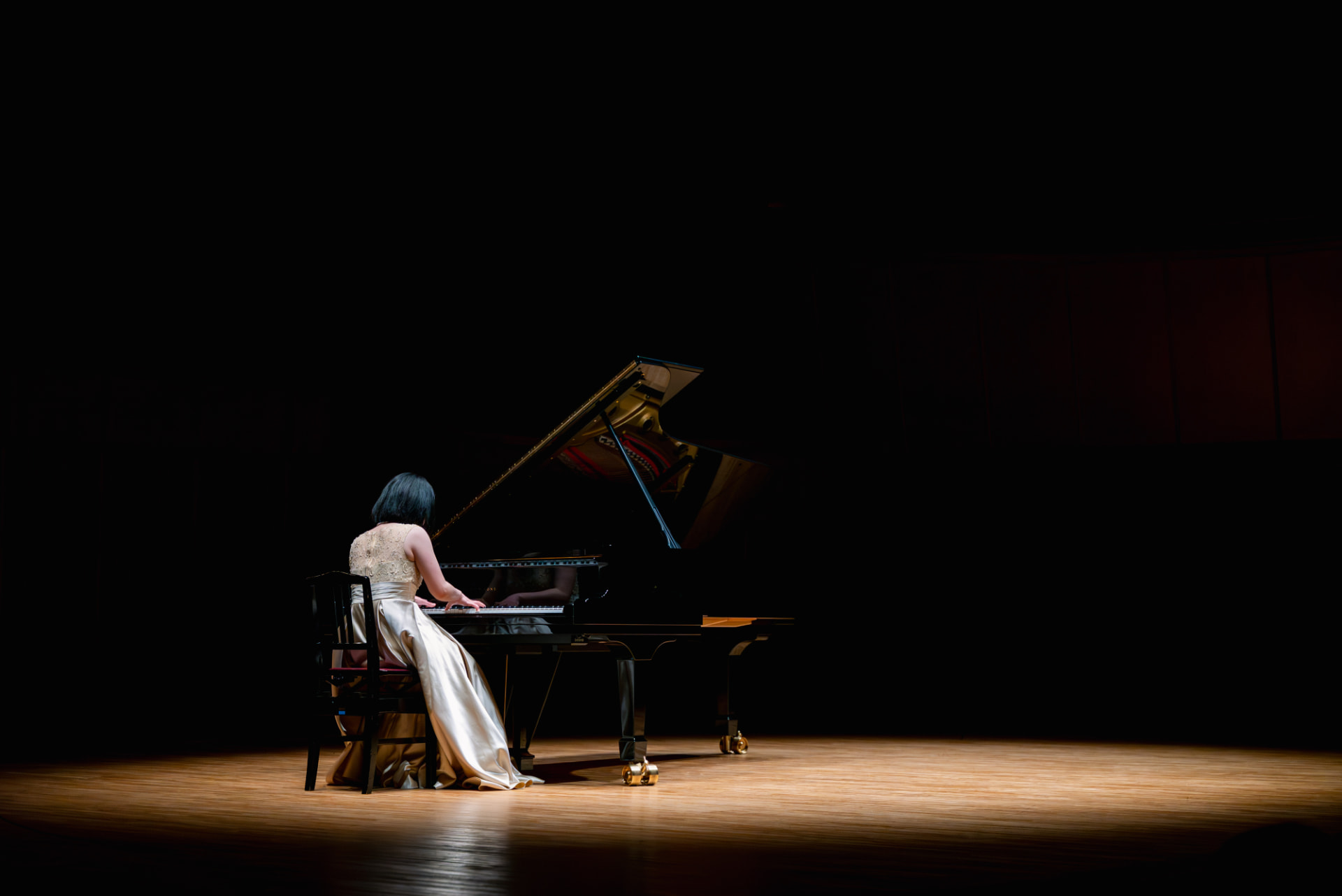Pianist in a gold gown performing on the concert hall stage