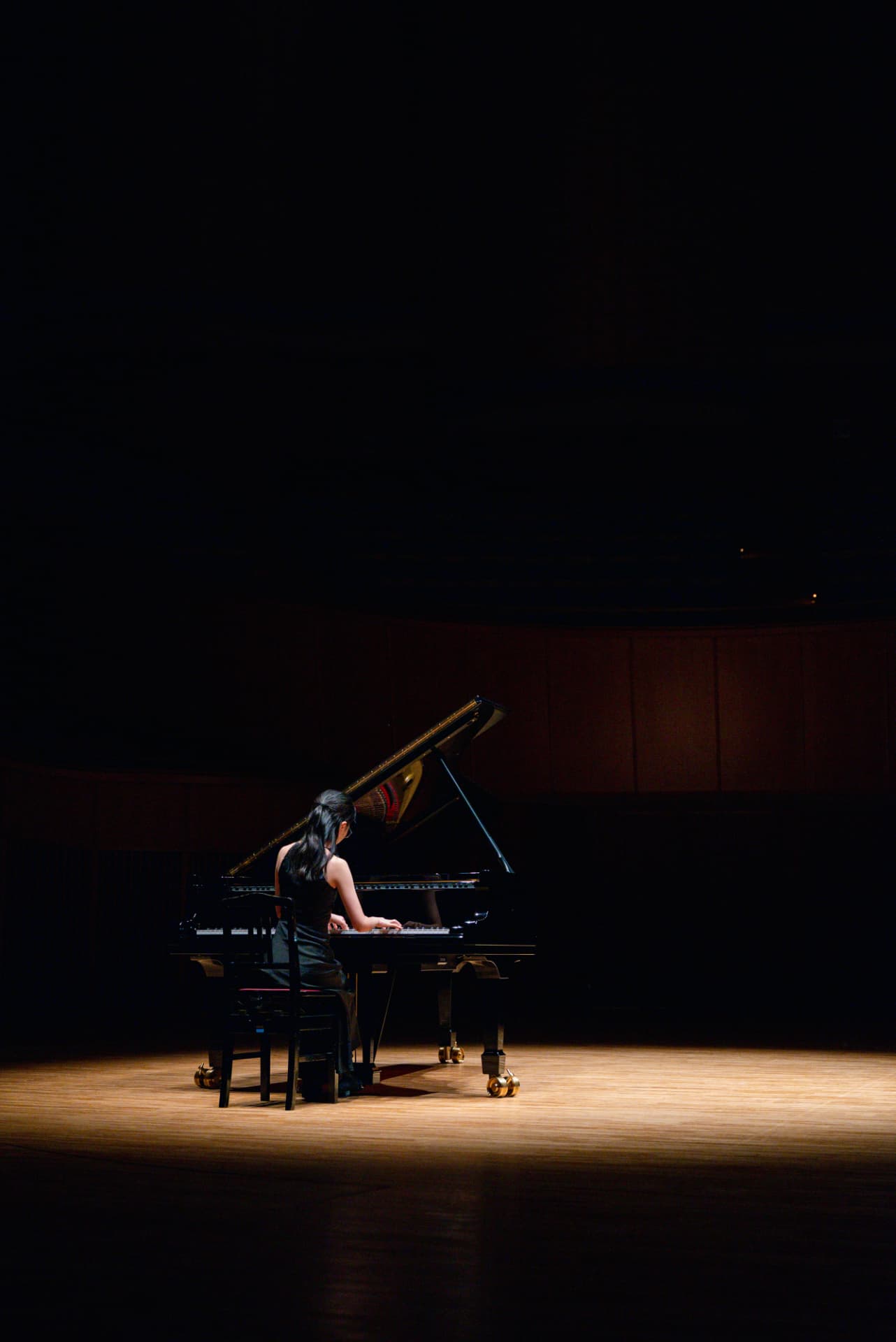 Pianist performing alone on a darkened concert stage