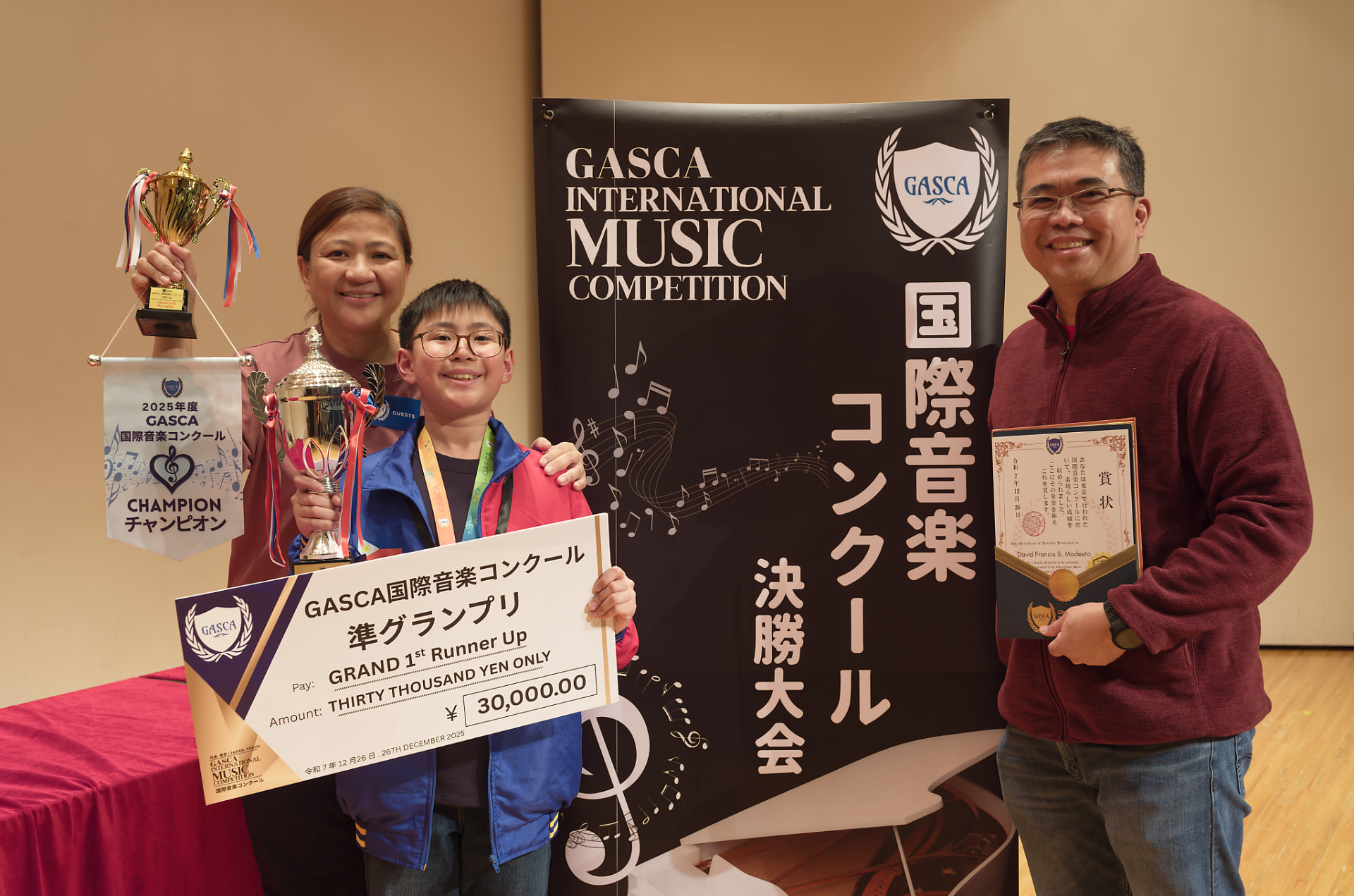 Young first runner-up holding a trophy and giant cheque with family