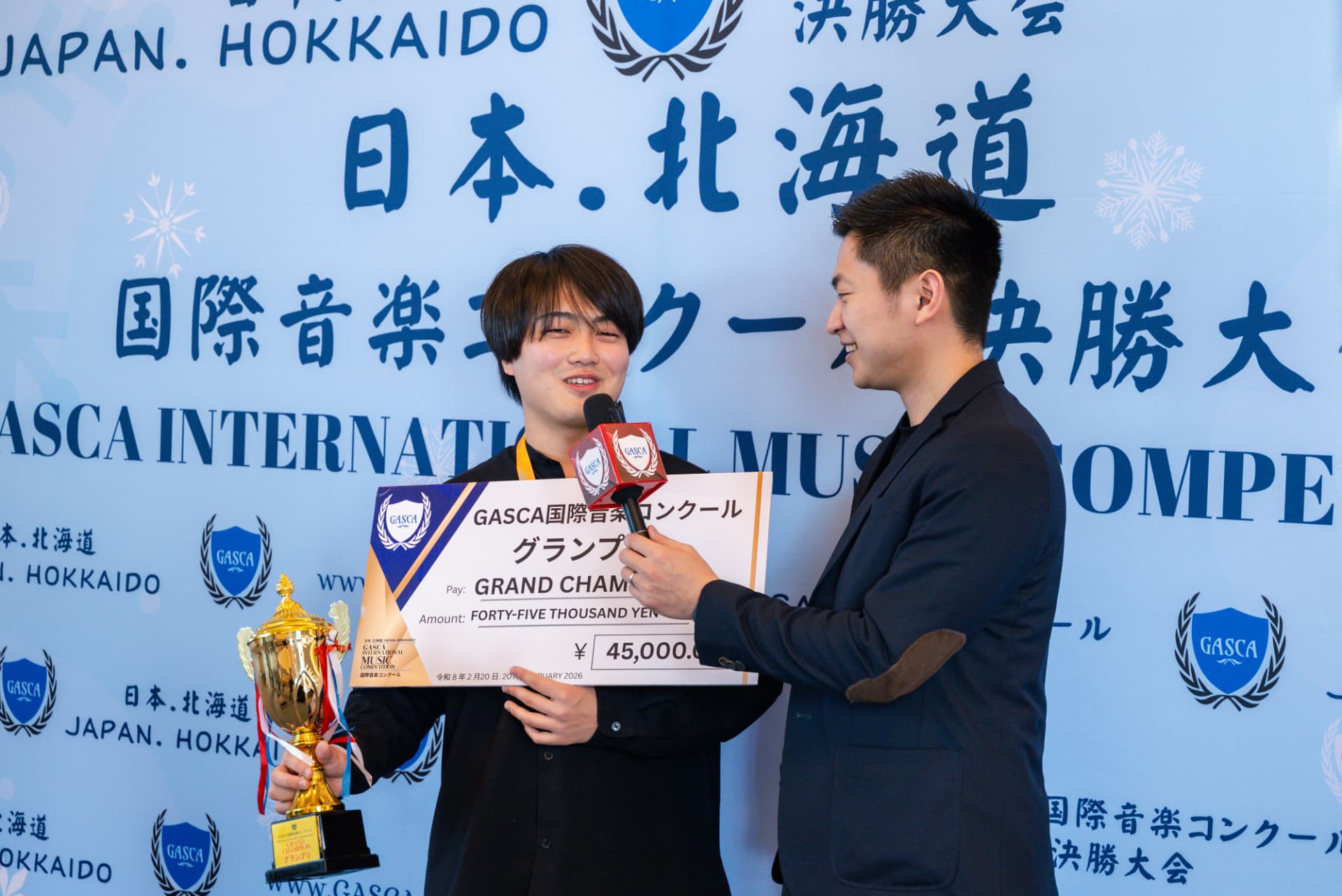 Hokkaido Grand Champion being interviewed with a trophy and giant cheque