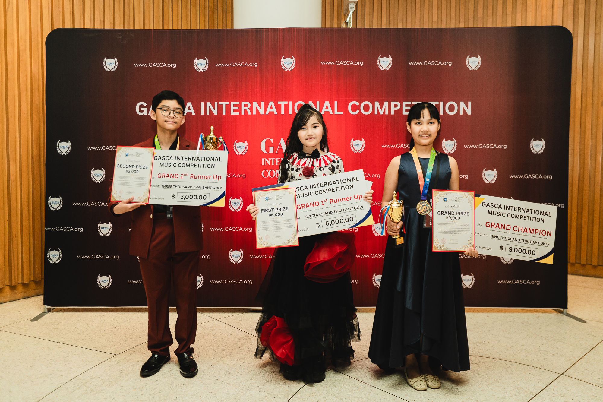 Three winners posing with trophies, certificates and giant cheques