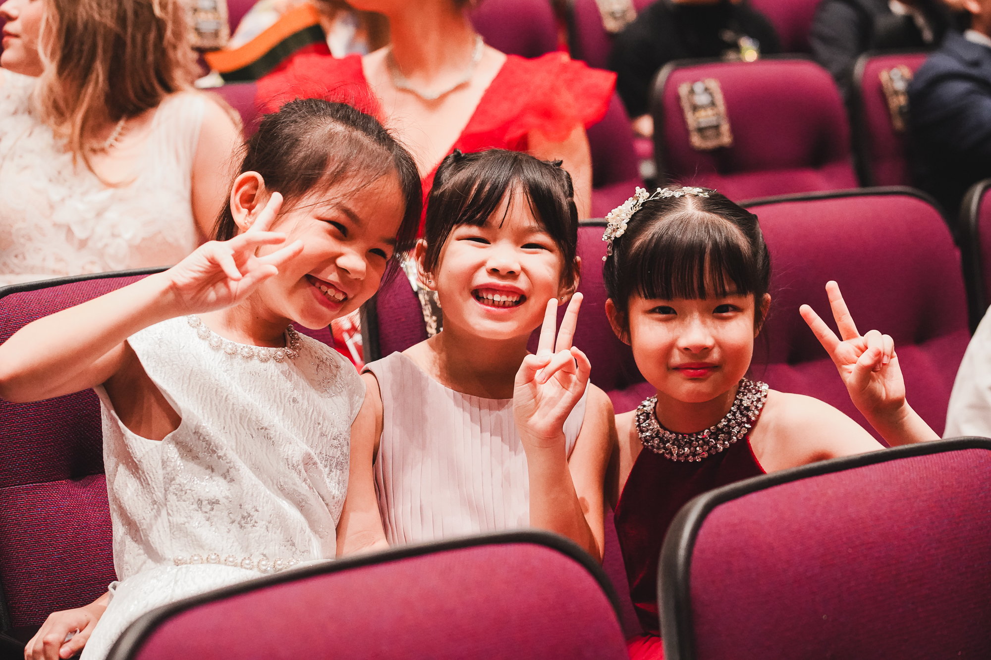 Three young contestants in formal dresses in the auditorium