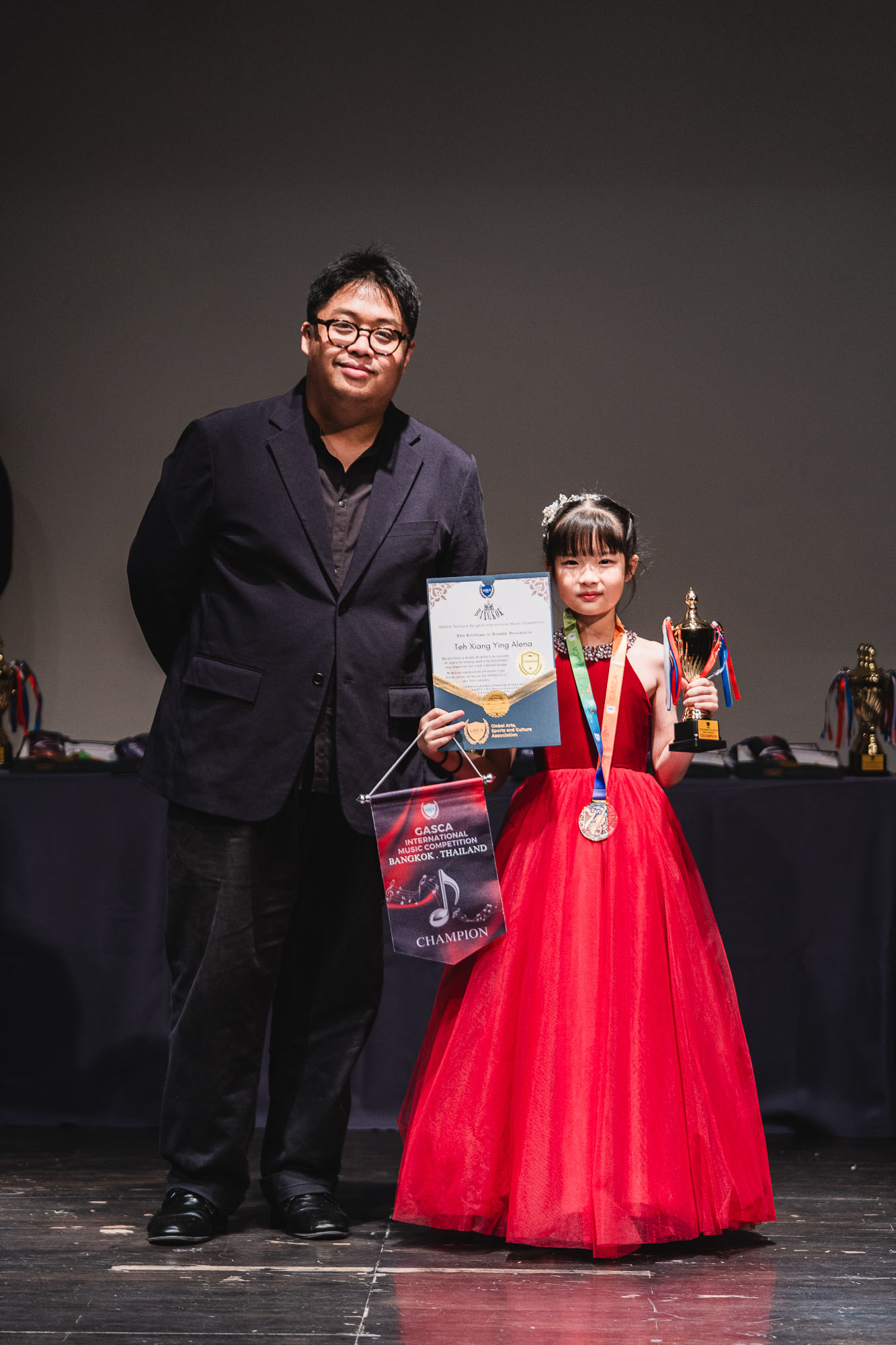 Young champion in a red dress with trophy and champion pennant
