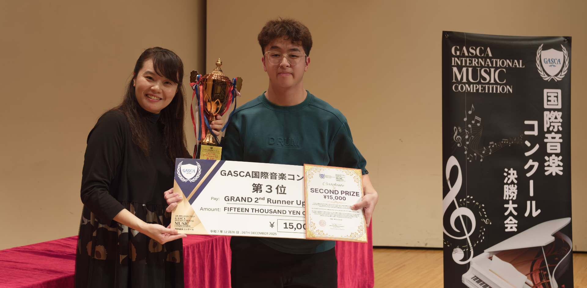 Second prize winner holding a trophy, certificate and giant cheque