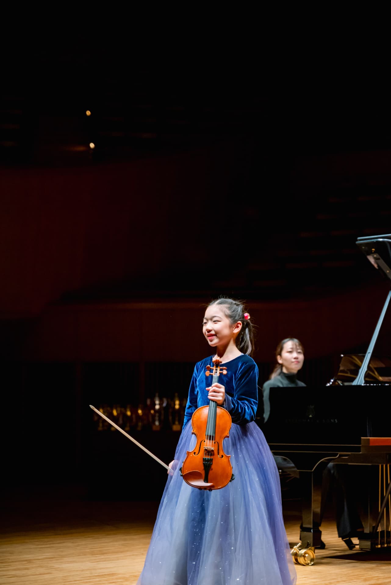 Young violinist smiling on stage after her performance