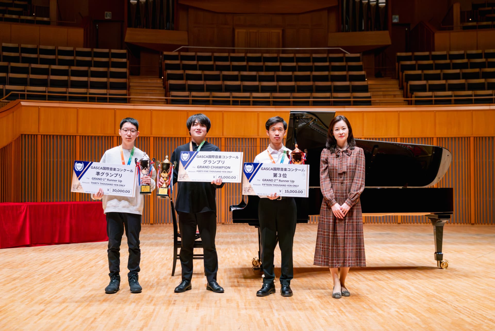 Three Grand prize winners on stage holding giant cash prize cheques