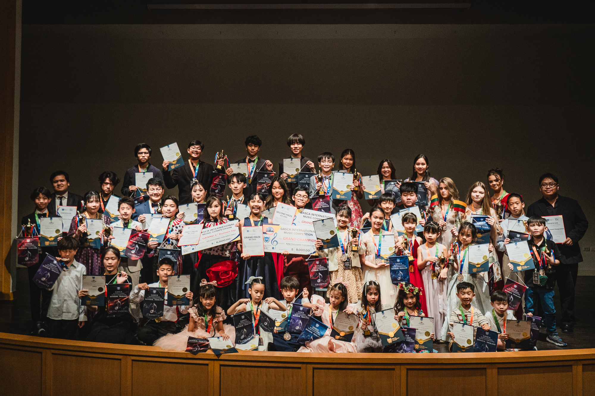 Large group of participants and winners on stage with awards and cheques